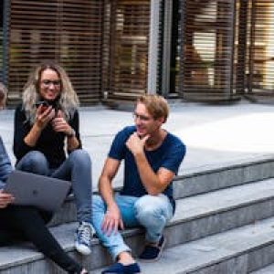 Three young professionals having a friendly chat while sitting on outdoor steps.